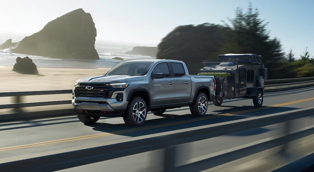A silver 2024 Chevy Colorado Z71 is shown towing a trailer.