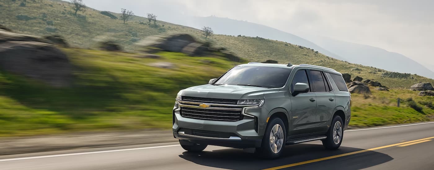 A grey 2024 Chevy Tahoe LT is shown driving on an open road.