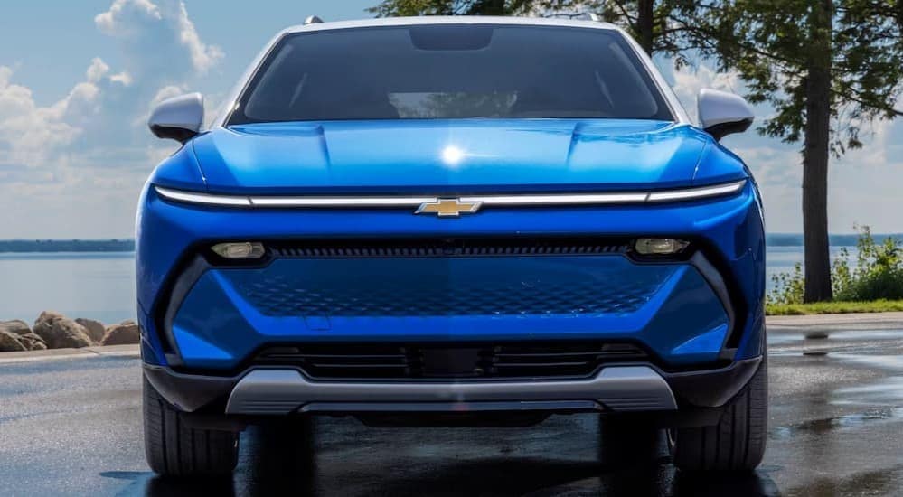 A blue 2025 Chevy Equinox is shown parked near water.