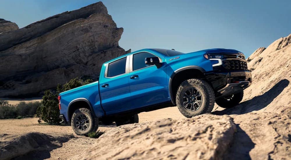 A blue 2025 Chevy Silverado 1500 ZR2 is shown off-roading.