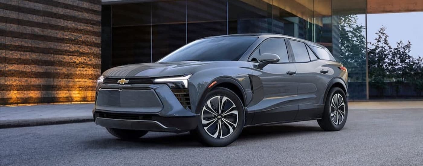 A gray 2024 Chevy Blazer EV for sale near Blacklick is shown parked near a wooden wall.