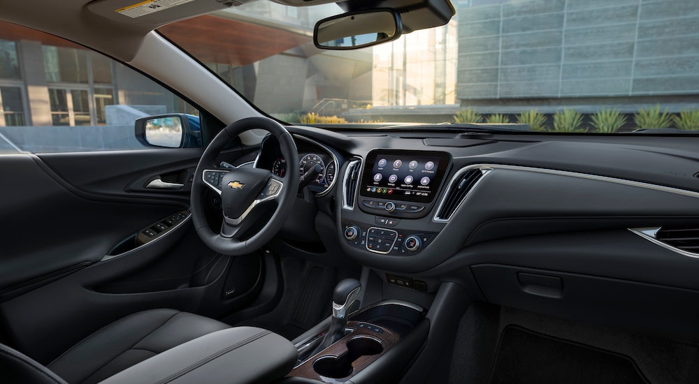 The black interior of a 2024 Chevy Malibu for sale is shown from the passenger side.