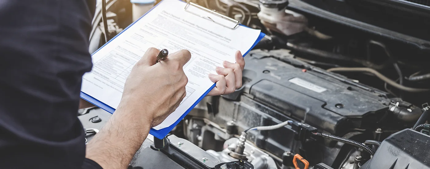 Service advisor writing up a repair estimate in front of a vehicle - Dave Gill Chevrolet helps Columbus Ohio drivers decide whether to keep repairing or replace