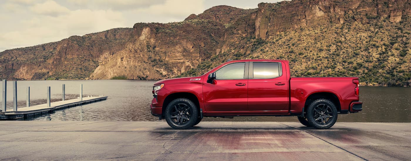 A red 2024 Chevy Silverado 1500 RST Z71 is shown from the side parked near a body of water.