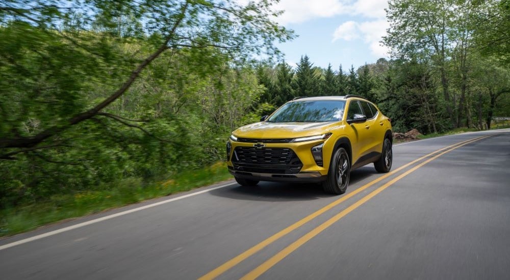 A yellow 2025 Chevy Trax ACTIV driving on a winding road.