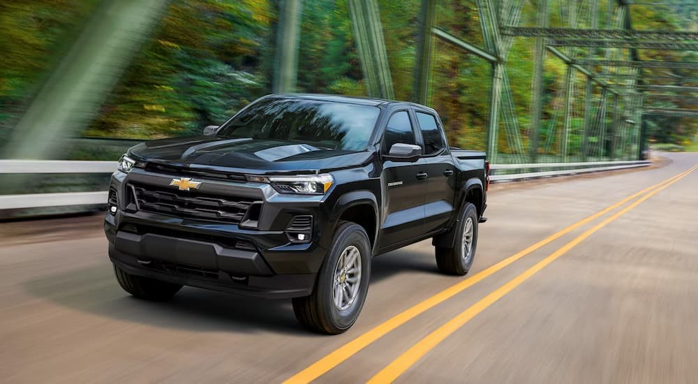 A black 2023 Chevy Colorado is shown driving on a bridge.