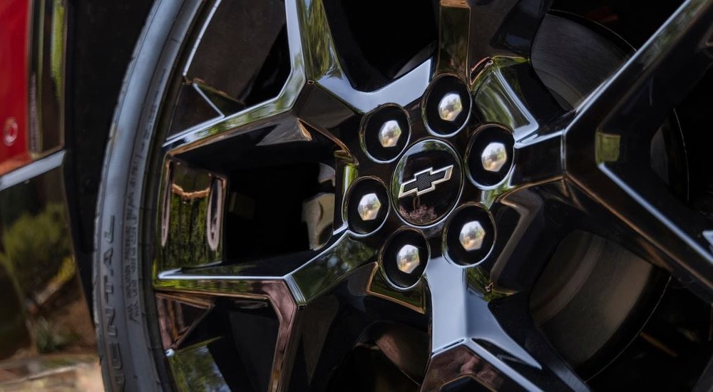 A close up shows a black wheel on a red 2024 Chevy Traverse RS.