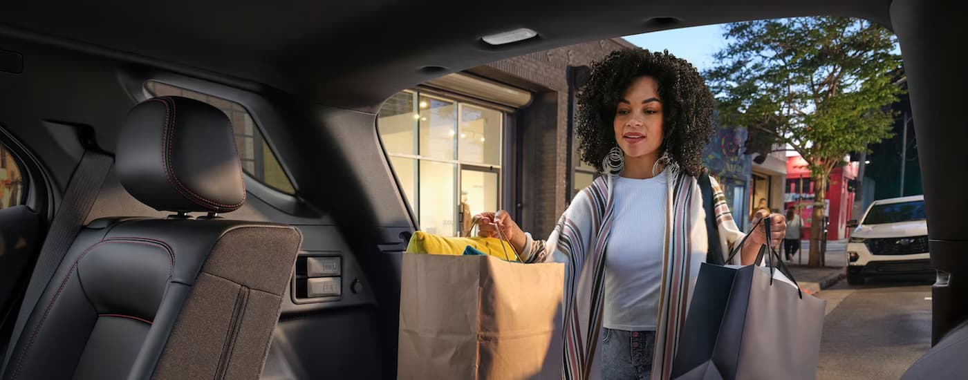 A woman is shown putting groceries into the rear of a 2024 Chevy Equinox.