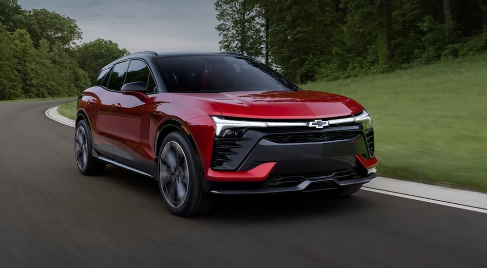 A red 2024 Chevy Blazer EV SS for sale is shown driving on a winding road.