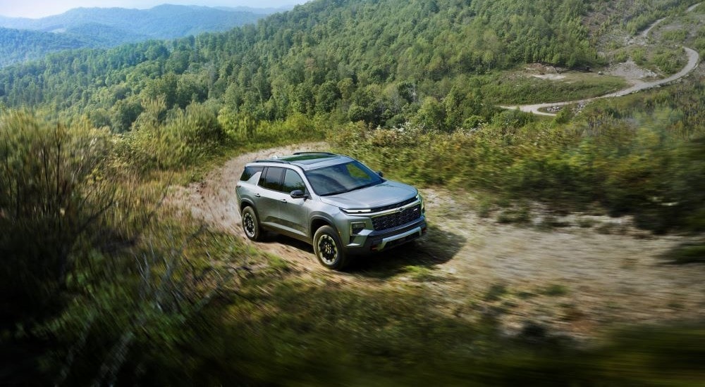 A grey 2024 Chevy Traverse Z71 is shown on winding trail after looking at SUVs for sale.
