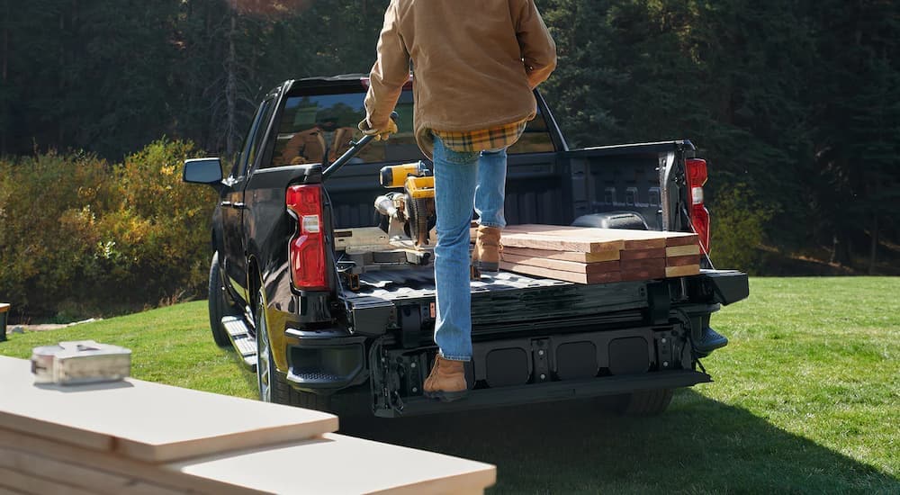 A man is shown stepping into the bed of a black 2022 Chevy Silverado.