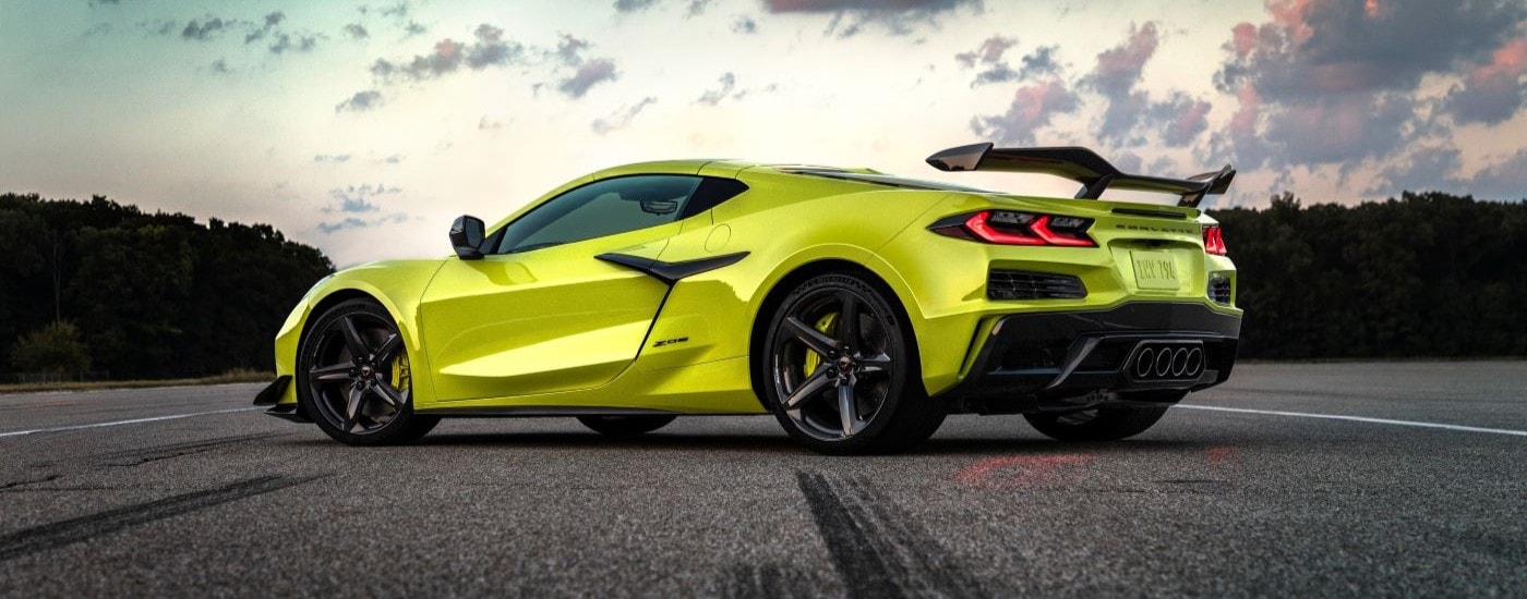 A neon yellow 2024 Chevy Corvette Z06 is shown parked on an empty lot on a cloudy day.