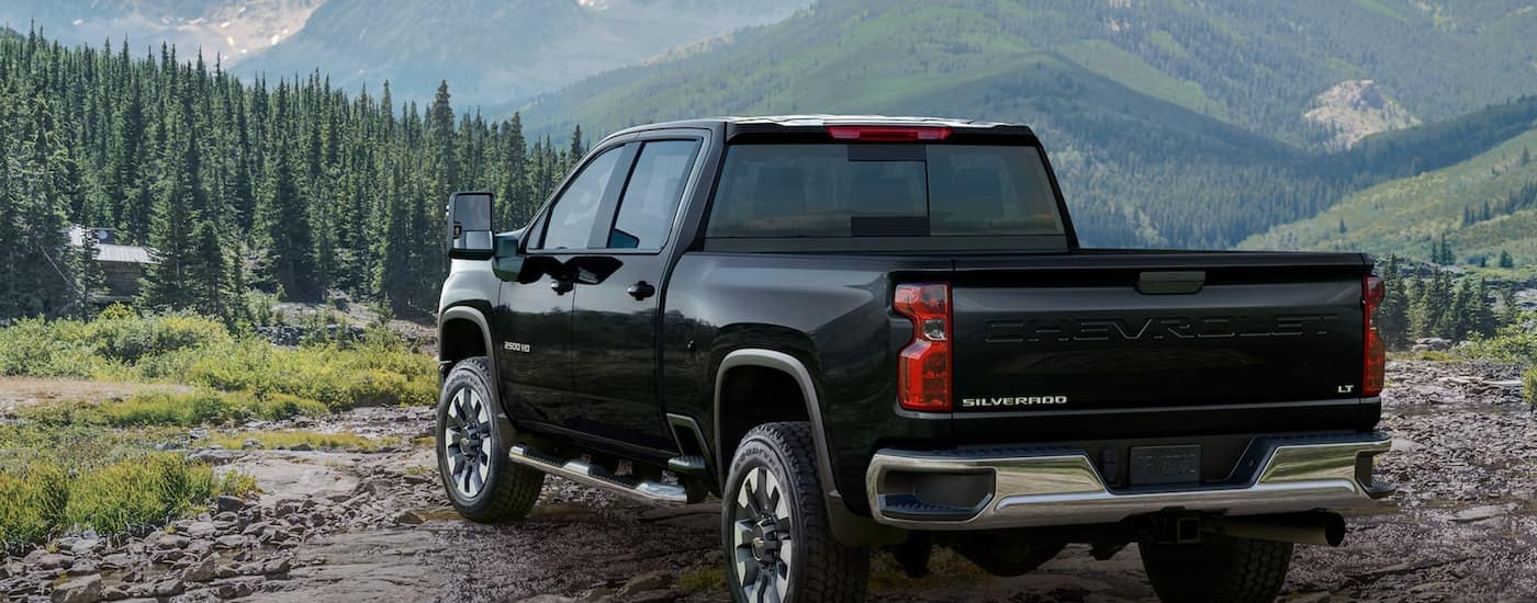 A black 2023 Chevy Silverado 2500HD LT is shown from a rear angle overlooking a mountain view.