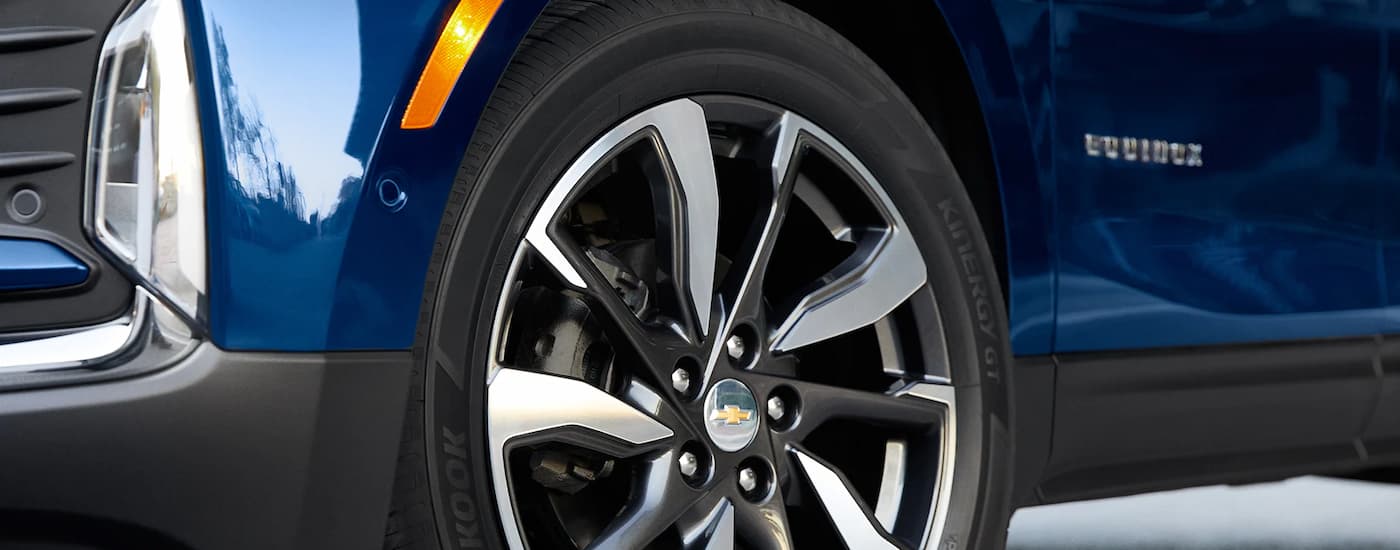 A close up of the tire and side of a blue 2023 Chevy Equinox is shown.