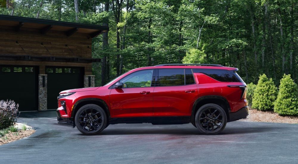 A red 2024 Chevy Traverse is shown parked near a house.