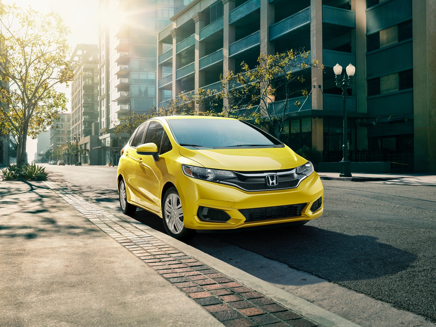 yellow Honda Fit parked next to a curb
