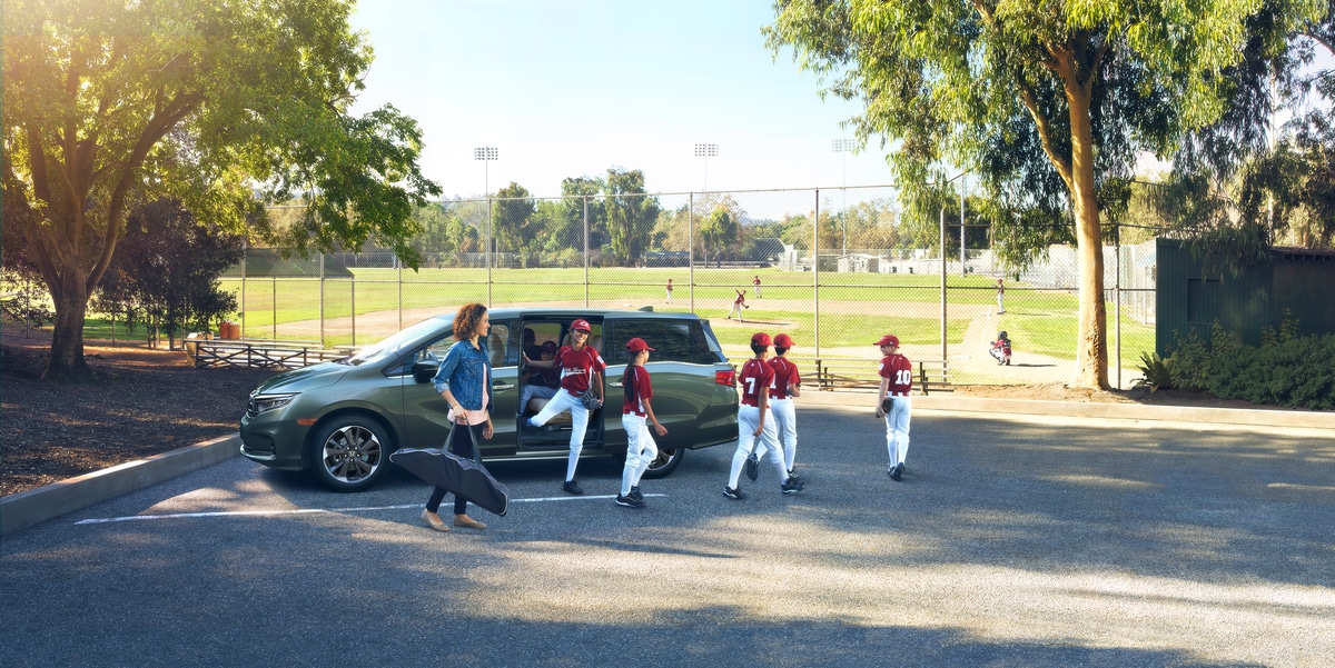 gray Honda Odyssey minivan parked at a baseball field