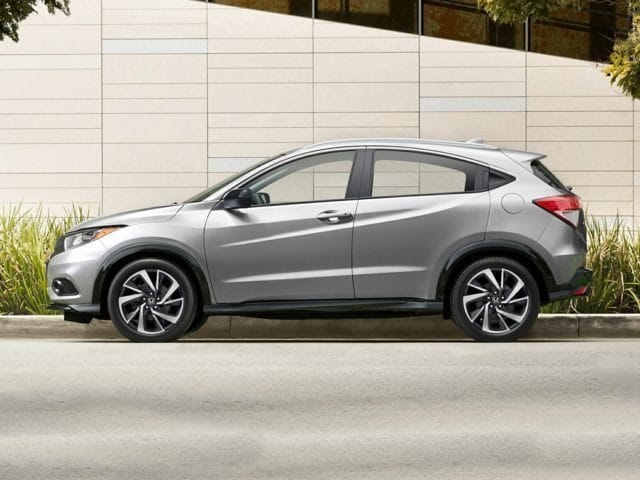 silver Honda HR-V SUV parked on the side of the road, next to a cement wall