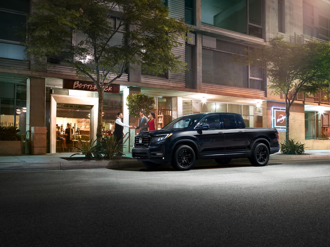 black Honda Ridgeline truck parked in front of a restaurant at night