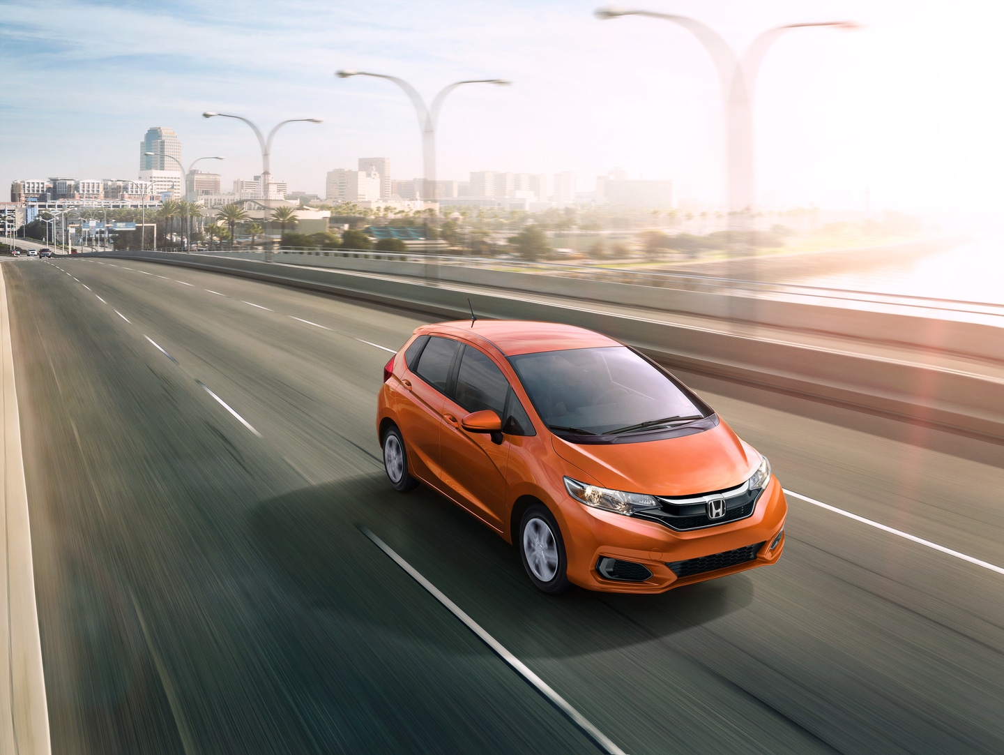 orange Honda Fit going over a bridge