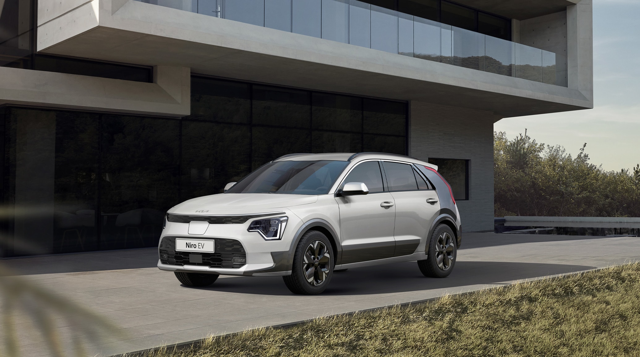 white Kia Niro EV parked in front of a modern home