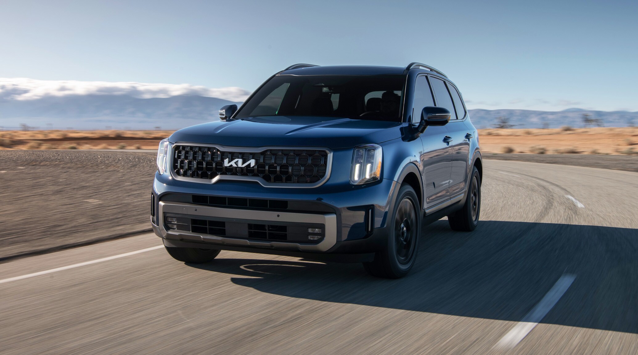 blue Kia Telluride SUV driving down a desert highway