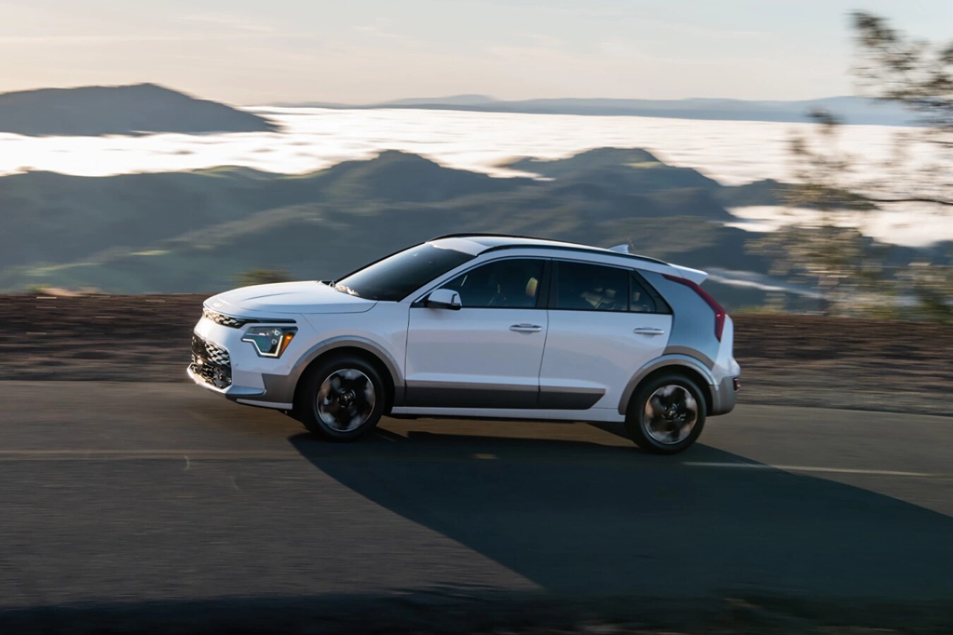 white Kia Niro EV driving by the coast