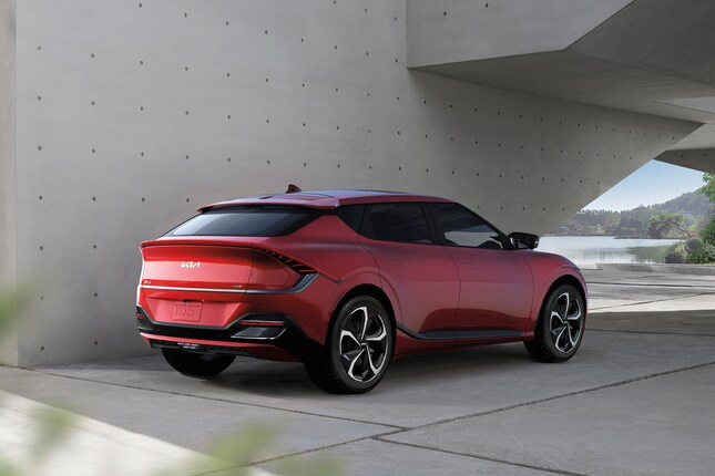 red Kia EV6 electric SUV parked in front of a modern cement building