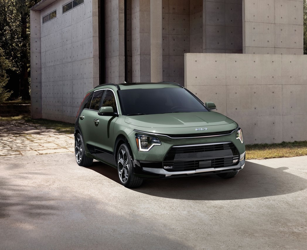 green Kia Niro SUV parked in front of a modern cement building