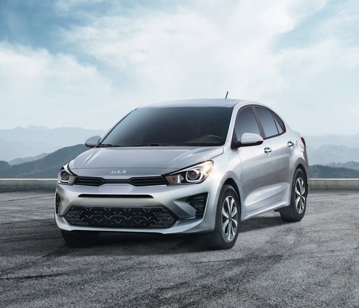 2016-KIA-Rio-SX-Sedan-L02.png silver Kia car parked on a cloudy backdrop