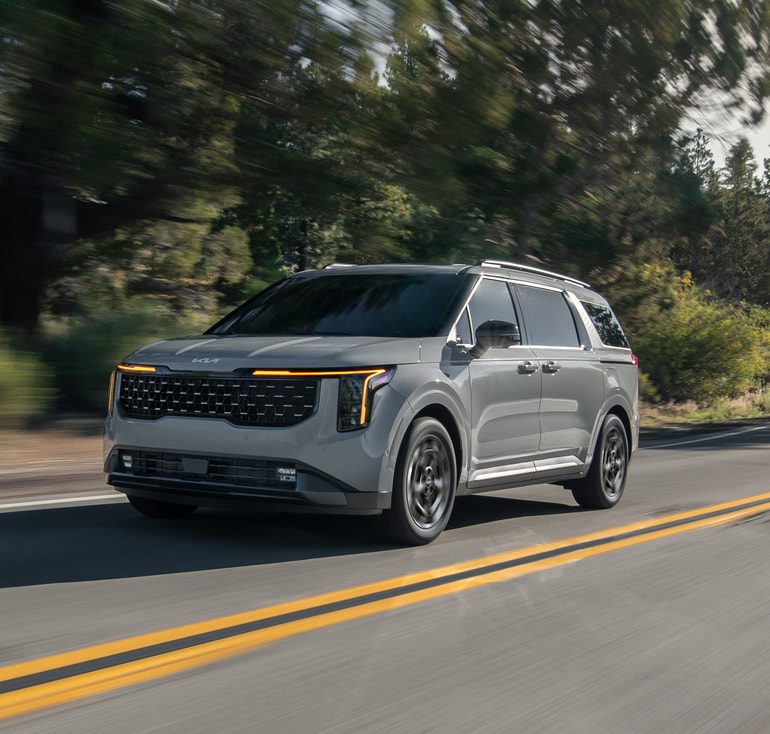 grey Kia Carnival driving