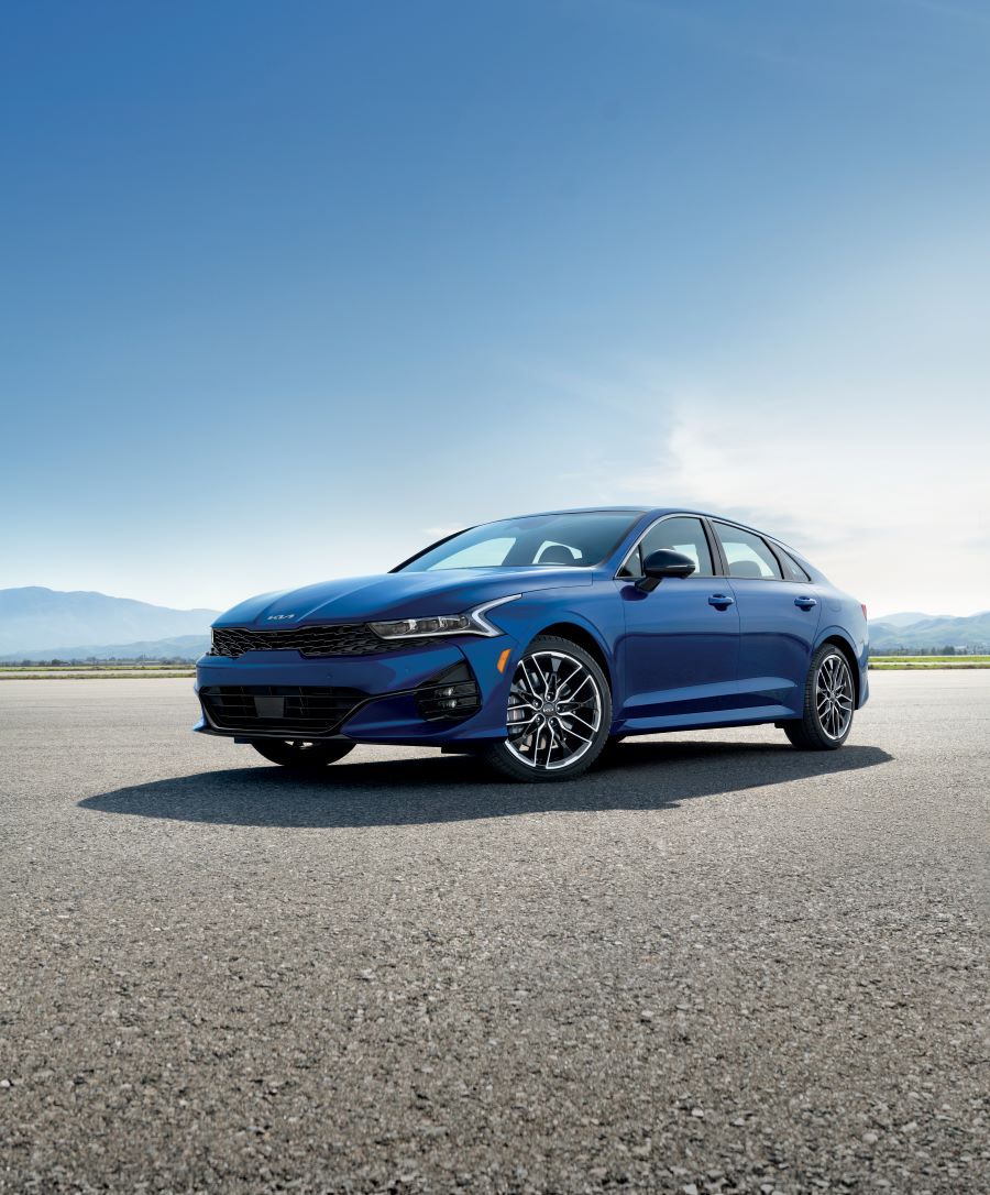 2021-Kia-K5-GTLine-AWD-Sedan.png blue Kia K5 sedan parked with a sunny-blue sky
