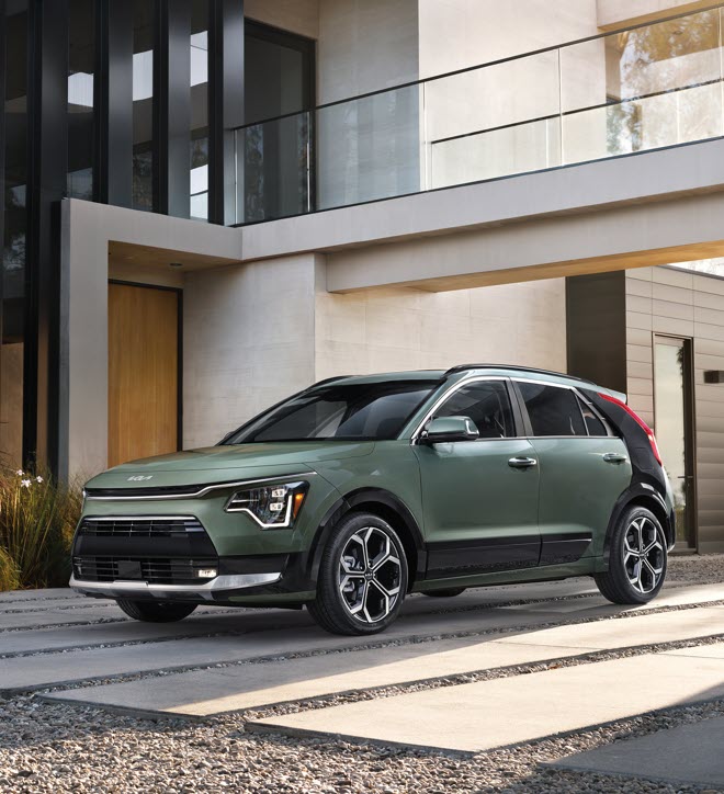 2019-KIA-NiroPlugIn-EXpremium-SUV-L01.png green Kia Niro EV parked in a driveway at a house