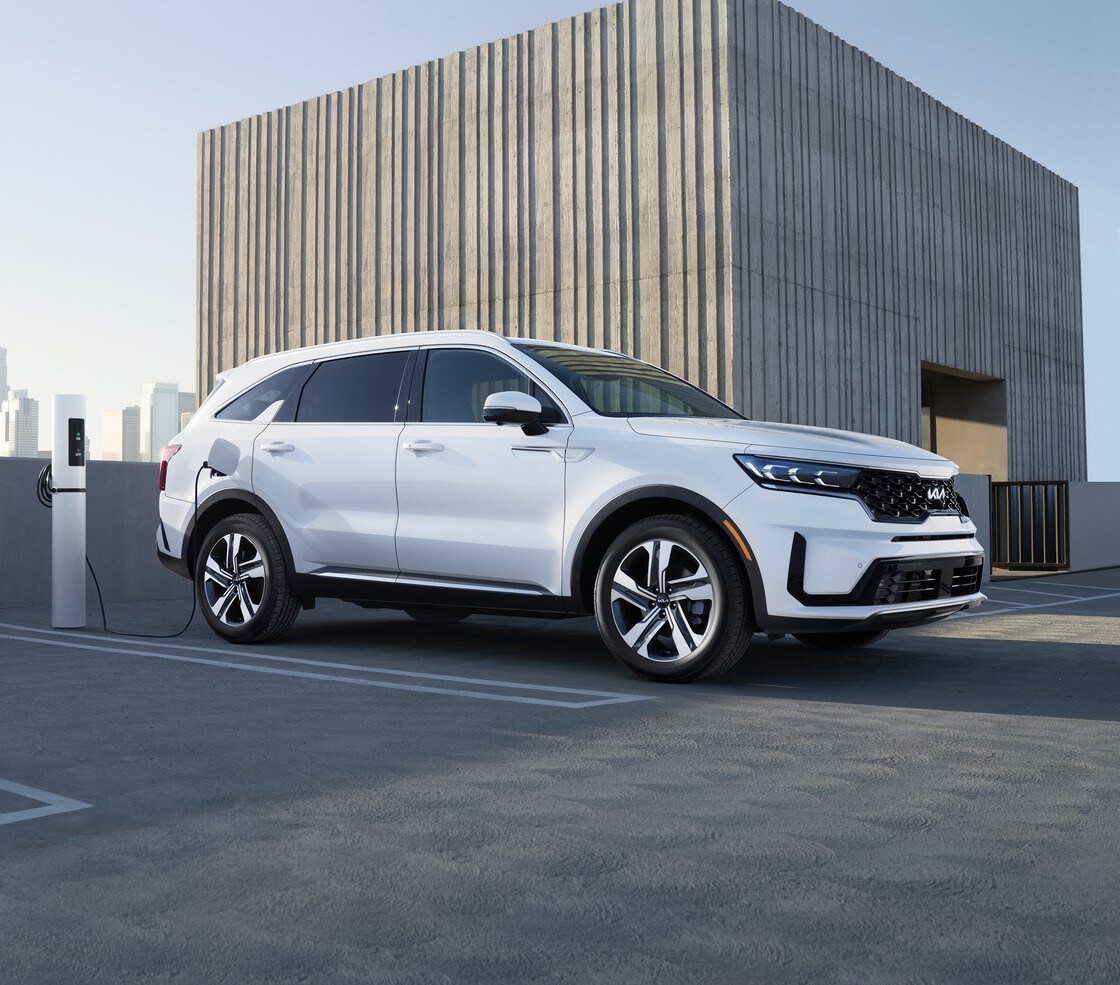 white Kia Sorento SUV parked on a rooftop, plugged into a charger