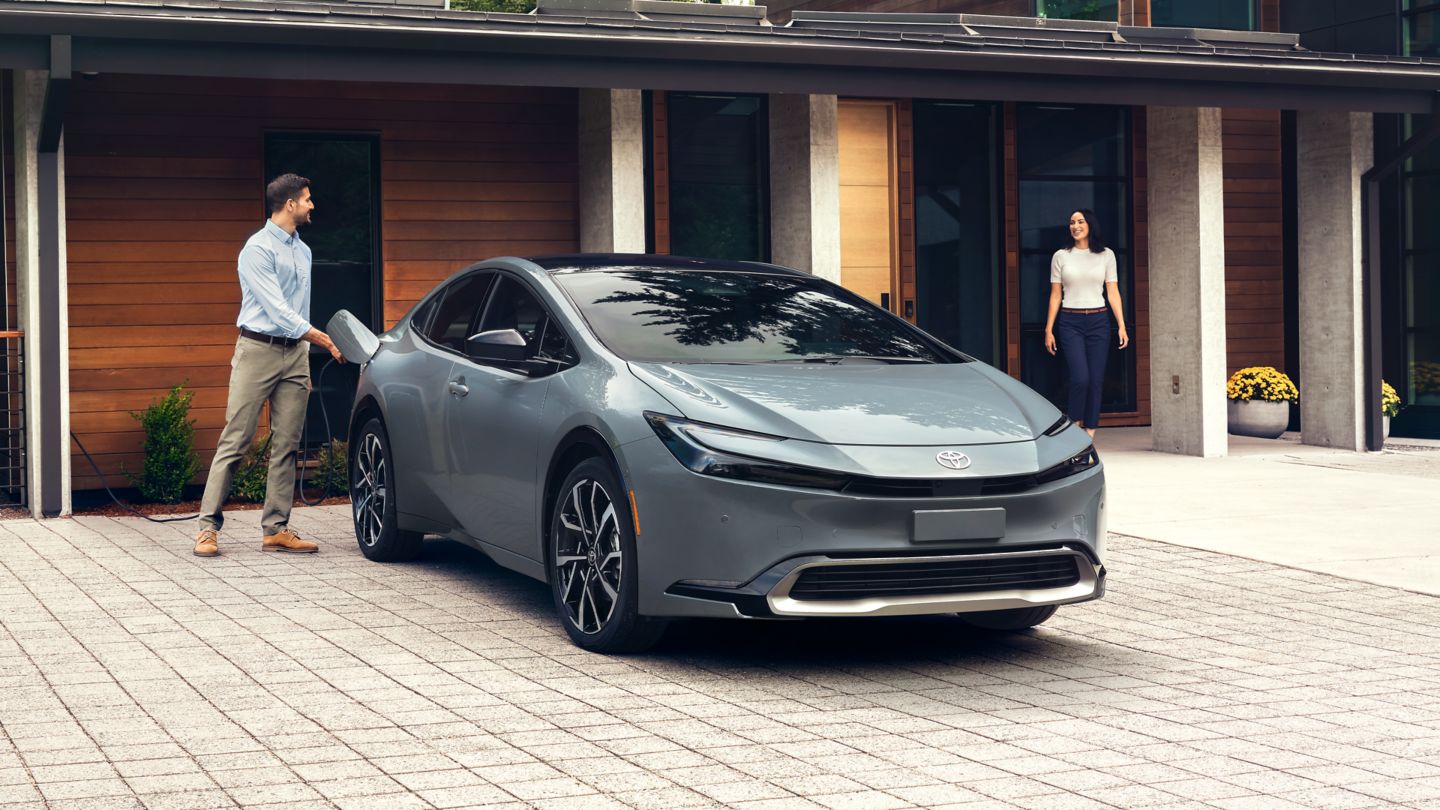 silver Toyota Prius Prime parked in the driveway with a couple talking
