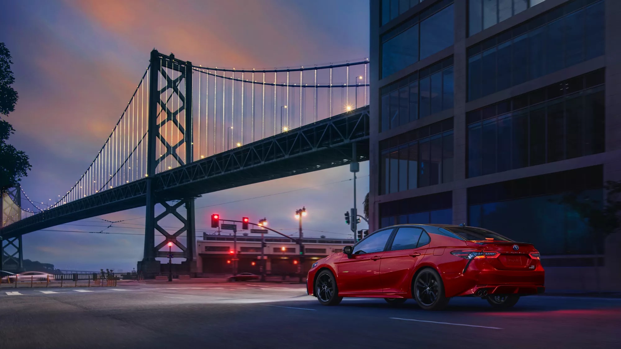 red Toyota Camry car parked next to a bridge at night