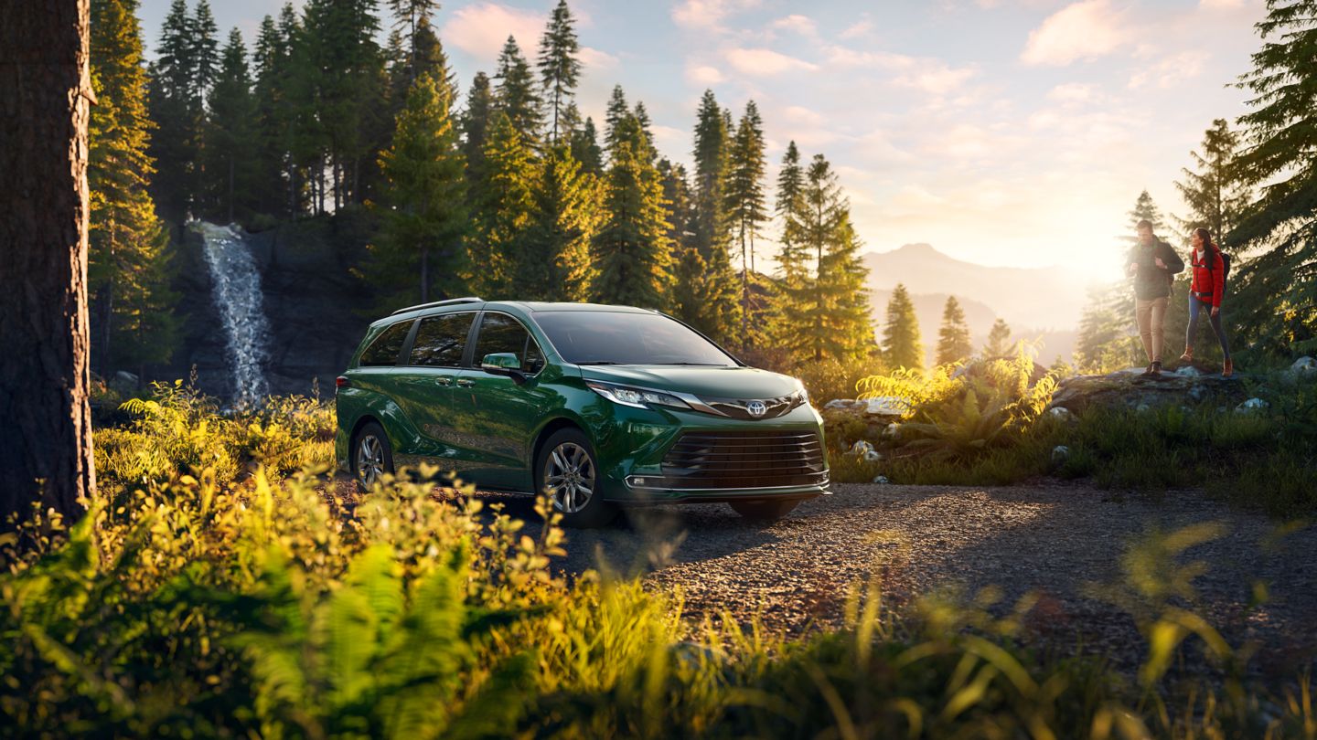 green Toyota Sienna parked in the woods with a couple walking nearby
