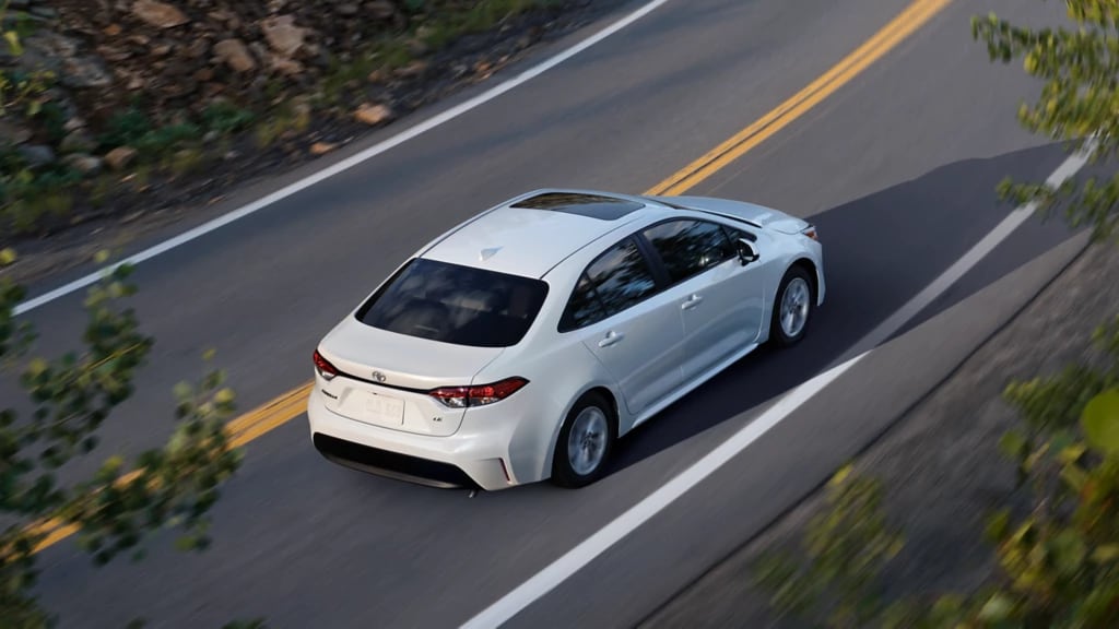 white Toyota car driving on the road, overhead shot