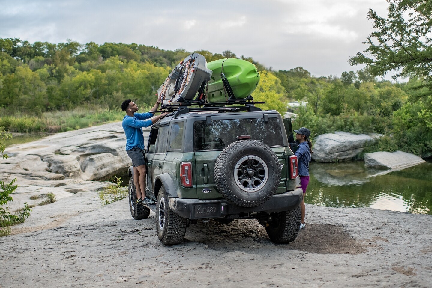 couple unloading canoes from roof rack on Ford Bronco