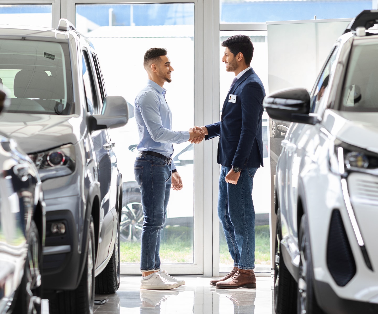 Chevy Dealer in Greensburg | Sales person shaking hands with a customer  inside of dealership 