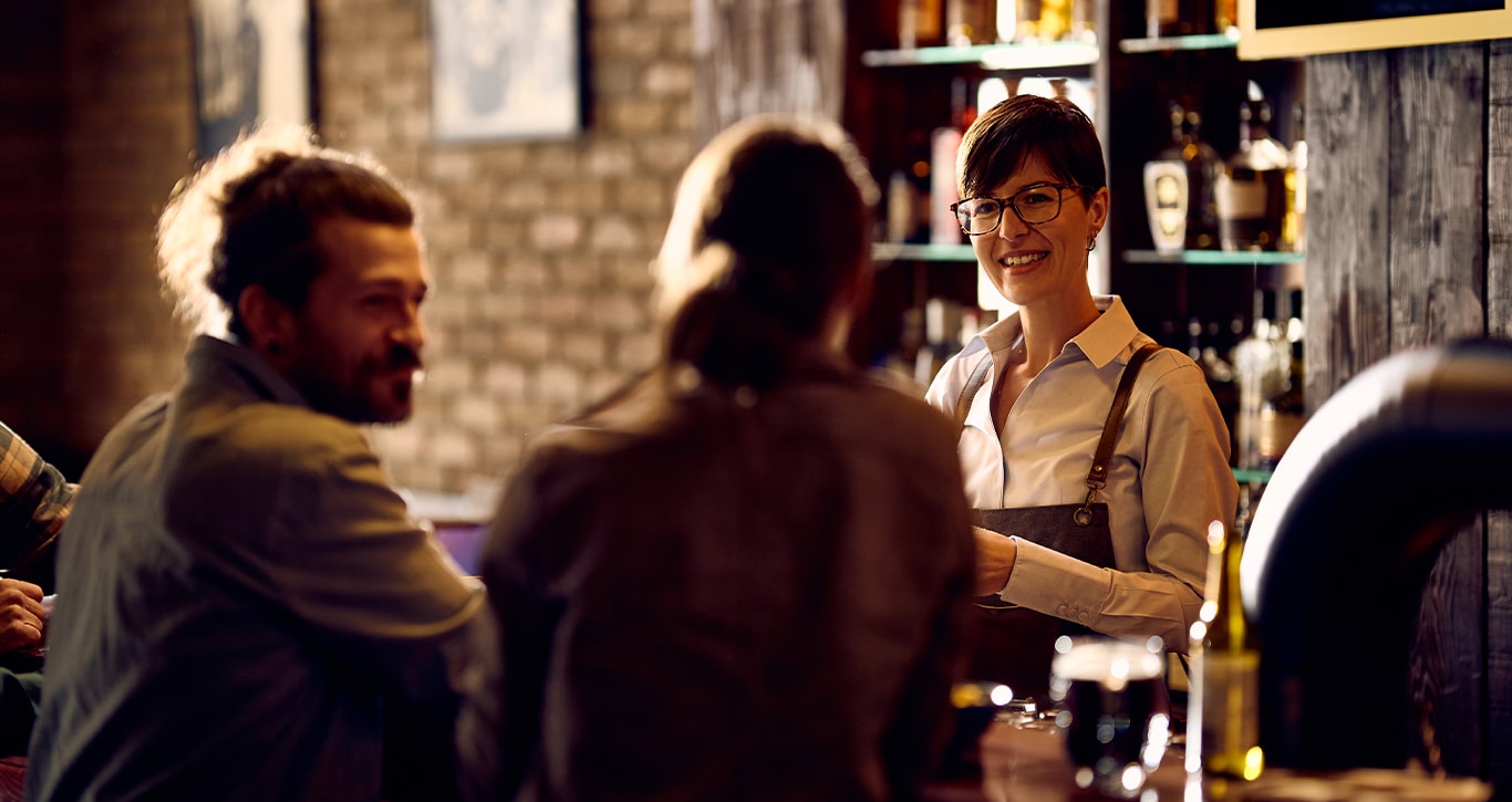 Nissan Dealer in Greensburg | Bartender smiling and talking to customer at the bar 