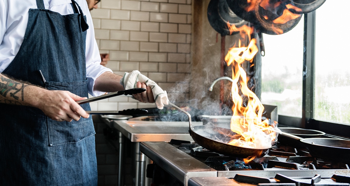 Nissan Dealer in Mt Pleasant | Person cooking on a stove with flames coming from the pan