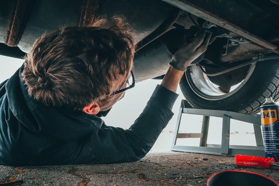 A mechanic under a Chevy vehicle performing some type of automotive service