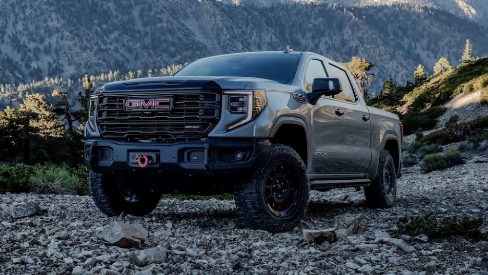   New GMC Sierra in the color grey driving around a rocky area filled with hills