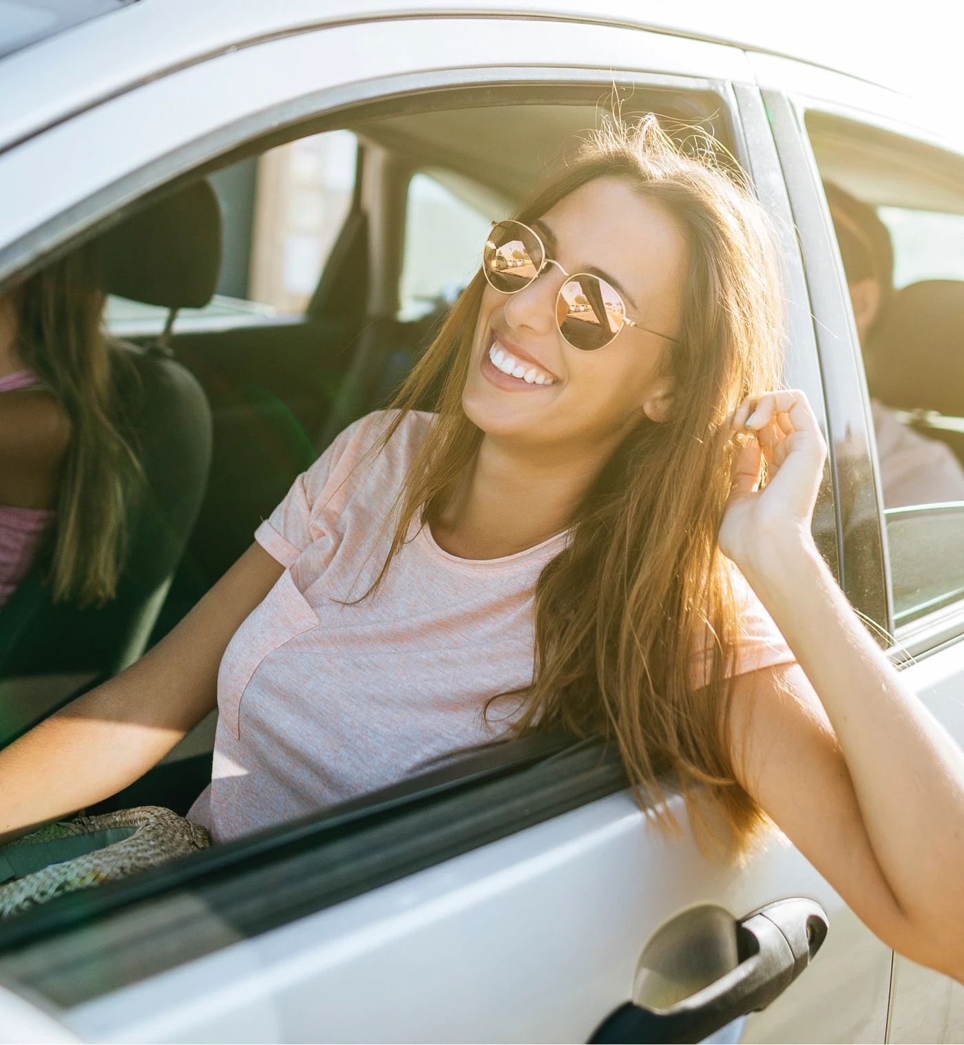 Smiling woman in sunglasses leaning out of a car window, Dennis & Co. Auto Group