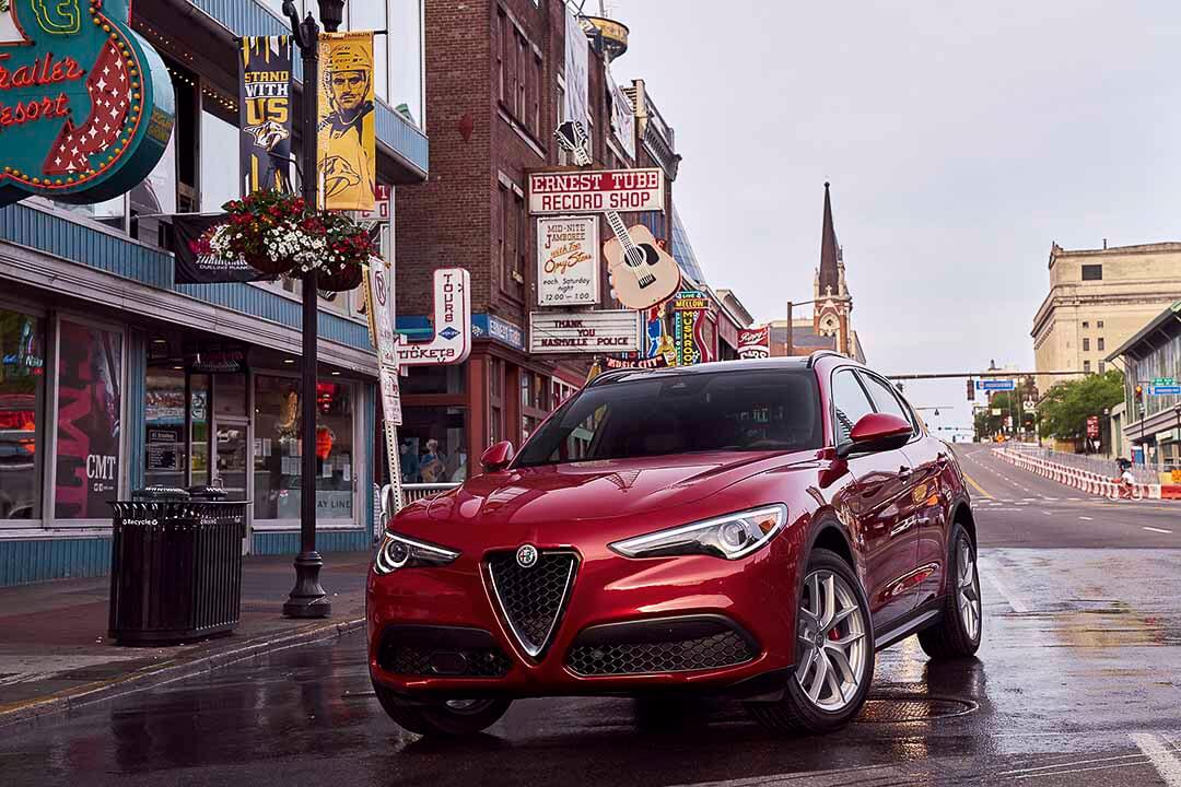 Vue 3/4 avant d'un VUS Alfa Romeo Stelvio 2019 rouge garé dans un centre-ville