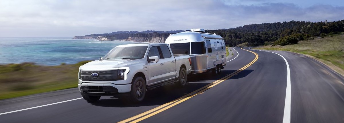 Silver F-150 Lightning towing an airstream on a coastal highway