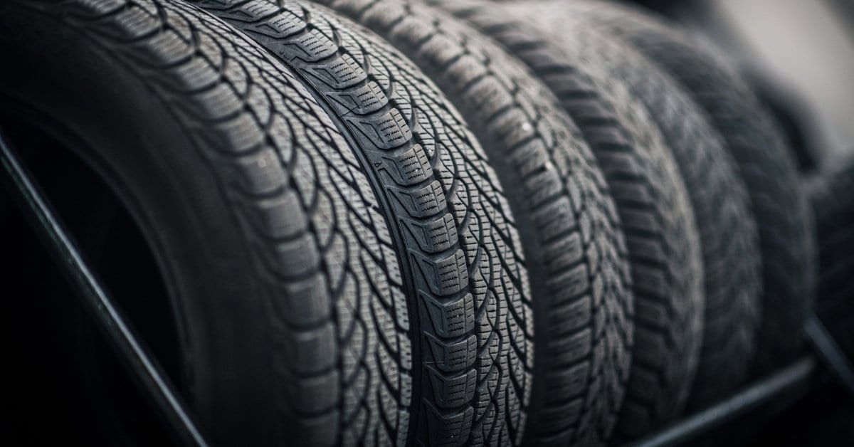 Close-up view of a row of new vehicle tires on a rack, highlighting detailed tread patterns and rubber texture.