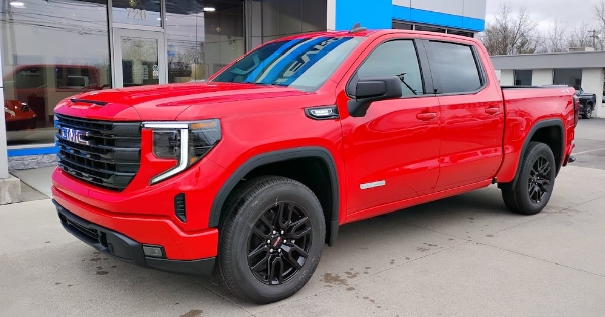 A bright red 2026 GMC Sierra 1500 Elevation crew cab pickup truck parked on a dealership lot, Don's Chevrolet GMC. The truck features black accents, including a black grille, wheels, and trim, with 