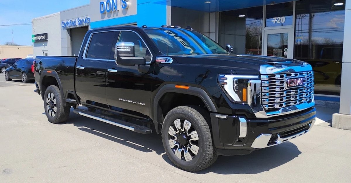  A black GMC Sierra 2500 Denali pickup truck parked outdoors in front of a dealership building with signage reading 